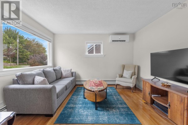 Living room with gray sofa, armchair, coffee table, blue rug, and hardwood floors. - 46 Adelaide Avenue, Halifax