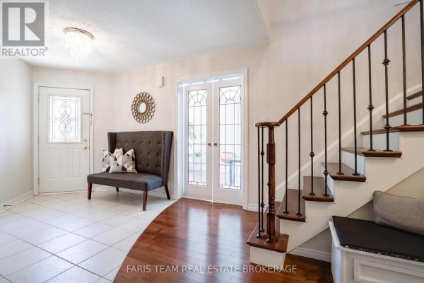 Foyer with white tile and hardwood floors, staircase, bench, and double glass doors. - 46 Bell Street, Barrie