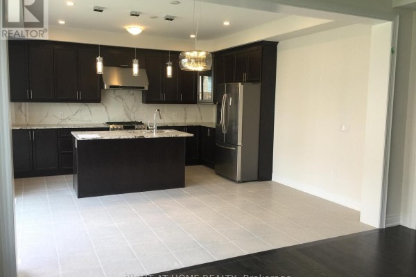 Open-concept kitchen and dining area with dark cabinets, stainless steel appliances, and light tile flooring. - 46 Blazing Star Street, East Gwillimbury