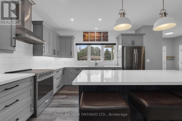 Living room in a grey bungalow with a large sectional sofa, fireplace, and view of the backyard. - 46 Brick Pond Road, Severn