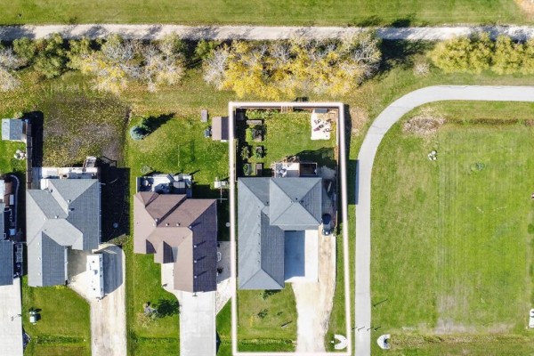 Aerial view of the property at 46 Carleton Drive, showing the house, backyard, and surrounding properties. - 46 Carleton Drive, Steinbach
