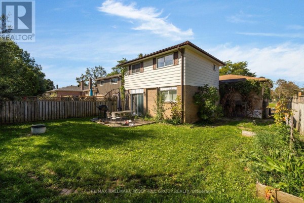 Backyard view of a house with a grass lawn, fence, patio, and barbecue. - 46 College Crescent, Barrie