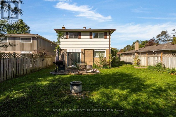Rear view of a two-story house with a backyard, patio, and detached garage. - 46 College Crescent, Barrie