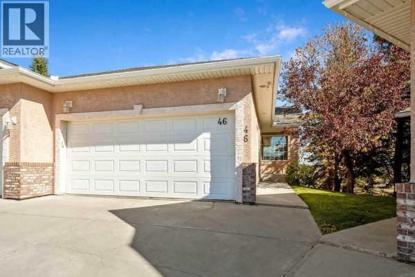 Exterior view of the duplex in daylight showing the garage door and entrance. - 46 Harvest Grove Green Ne, Calgary