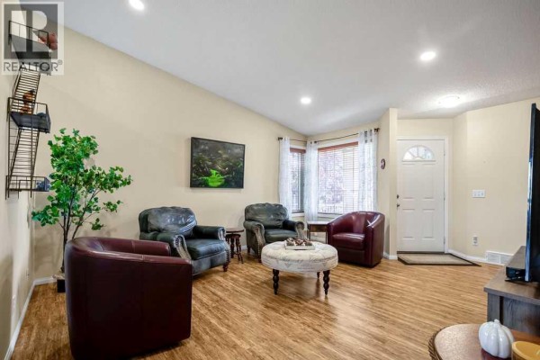 Living room furniture arrangement with leather chairs, ottoman, and a view towards the entrance. - 46 Harvest Grove Green Ne, Calgary