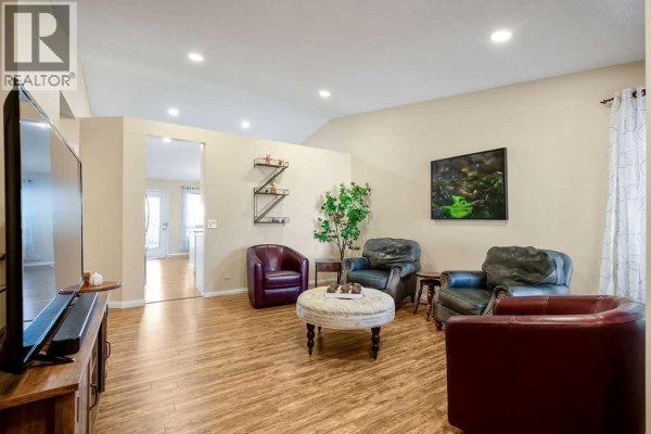 Living room with multiple seating areas, a television, and an open doorway to another room. - 46 Harvest Grove Green Ne, Calgary
