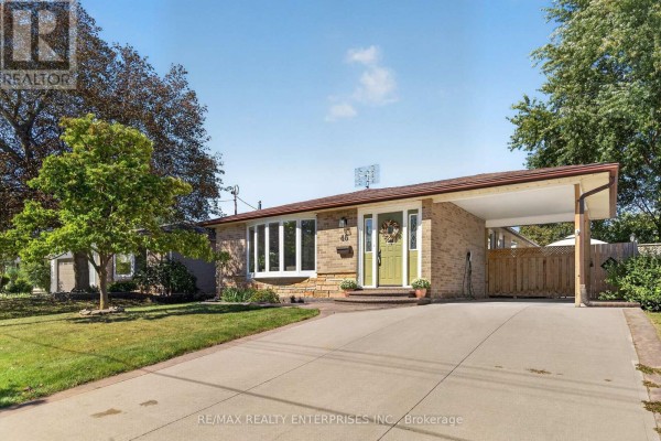 Wide aerial view of a bungalow with brick exterior, bay window, green front door, and covered carport. - 46 Marilyn Crescent, Halton Hills