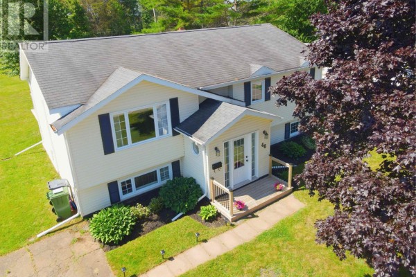 Aerial view of a yellow two-story house with a dark tree in the foreground. - 46 Northridge Parkway, Charlottetown