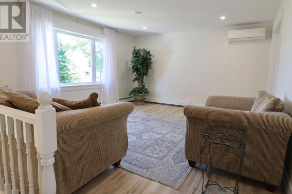 Living room with two upholstered chairs, a patterned rug, and a large window. - 46 Northridge Parkway, Charlottetown
