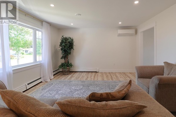 Living room with light wood floors, patterned rug, and two upholstered chairs. - 46 Northridge Parkway, Charlottetown