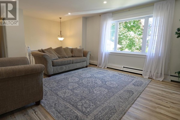Living room with a sofa, upholstered chairs, patterned rug, and large window. - 46 Northridge Parkway, Charlottetown