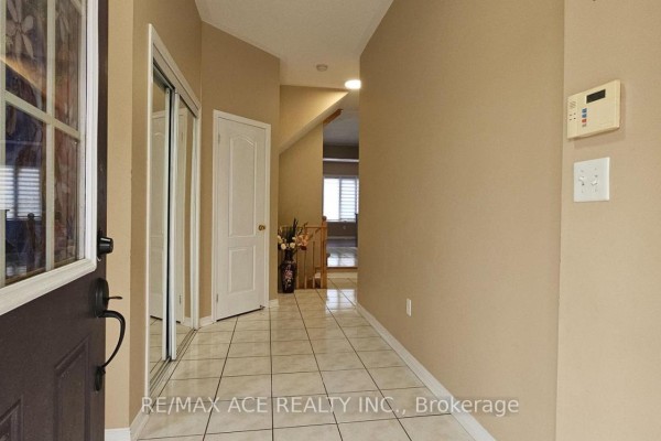 Foyer with beige walls, tiled floor, mirrored closet, and doorway to stairs. - 46 Ralph Chalmers Avenue, Markham