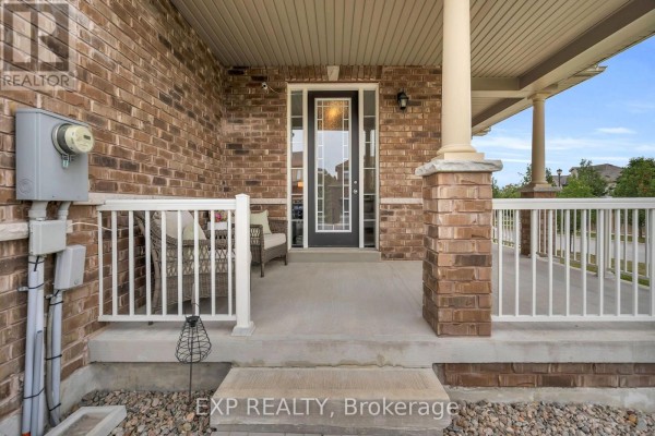 Close-up of a covered front porch with brick pillars, white railings, and a glass-paned front door. - 46 Rennie Street, Brock