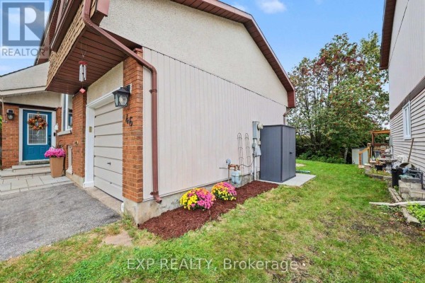 Side view of the townhouse exterior showing a utility box and lawn. - 46 Westcliffe Street, Ottawa