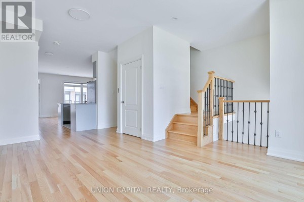 Interior view from the front door looking up a wooden staircase with dark tile flooring and white walls. - 46 William Saville Street, Markham