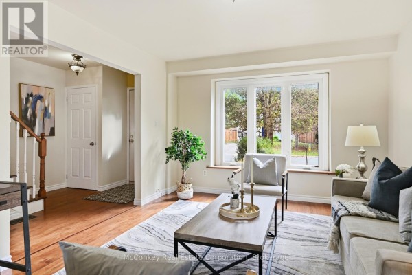 Living room with hardwood floors, sofa, chairs, and view of the entrance hallway. - 460 Cardinal Drive, Peterborough
