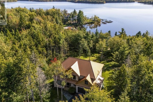 Aerial view of a house with a copper roof, surrounded by trees, overlooking a lake. - 460 Mccabe Lake Drive, Middle Sackville