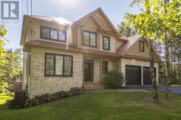 Exterior front view of a modern house with stone and wood siding and a three-car garage. - 460 Mccabe Lake Drive, Middle Sackville