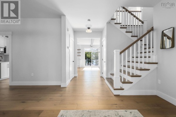 Interior view of a bright home foyer with light wood floors, white walls, and a staircase. - 460 Mccabe Lake Drive, Middle Sackville
