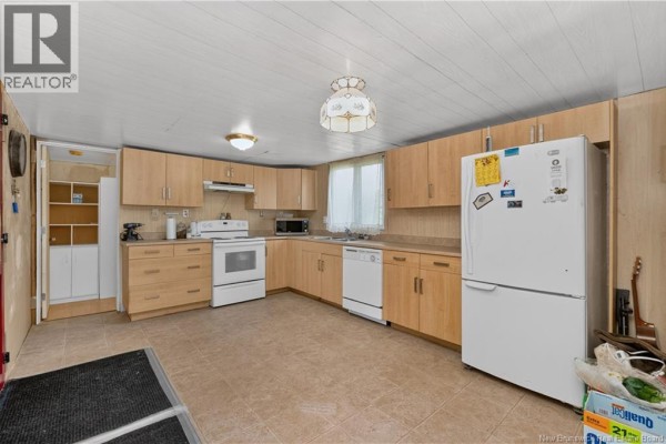 L-shaped kitchen featuring light wood cabinets, white appliances, and beige tiled floors leading into an adjacent room. - 460 Middlesex, Colpitts Settlement