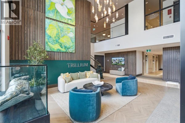 Modern apartment building lobby with abstract art, seating area, and wood paneled walls. - 460 Nicola Street Unit# 1004, Kamloops