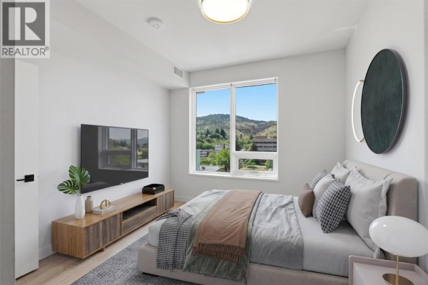 Bedroom with a queen-size bed, large window with a view, and mounted television. - 460 Nicola Street Unit# 1004, Kamloops