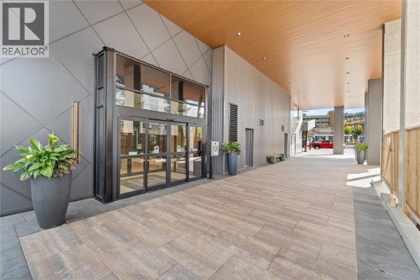 Entrance to the apartment building with automatic glass doors and tiled walkway. - 460 Nicola Street Unit# 1201, Kamloops