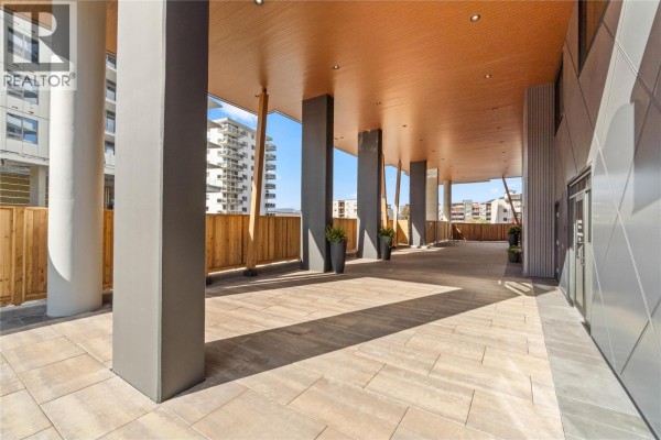 Covered outdoor walkway with stone flooring, large pillars, and wooden railings. - 460 Nicola Street Unit# 1201, Kamloops