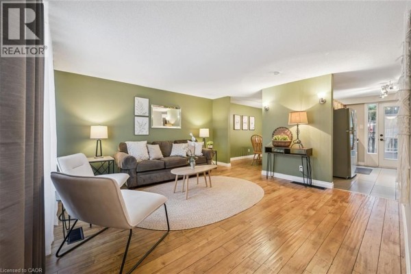 Living room with light green walls, hardwood floors, a sofa, chairs, and a round rug. - 460 Parkview Crescent, Cambridge