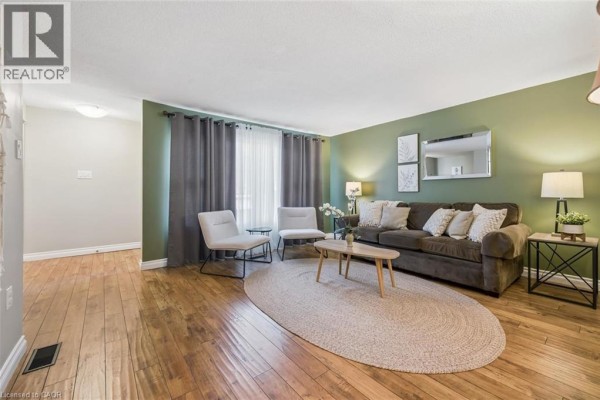 Living room with two sofas, chairs, a macrame wall hanging, and hardwood floors. - 460 Parkview Crescent, Cambridge