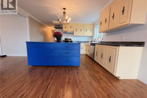 Kitchen with yellow cabinets, white tiled backsplash, and a blue island with drawers. - 460 Vanier Street, Campbellton