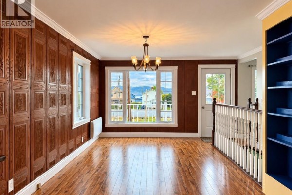 Dining area with wood-paneled walls, large windows overlooking a street, and a chandelier. - 460 Vanier Street, Campbellton