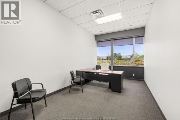 Side view of a commercial building with a large tree in front. - 4600 Rhodes Drive Unit# #4 Office, Windsor