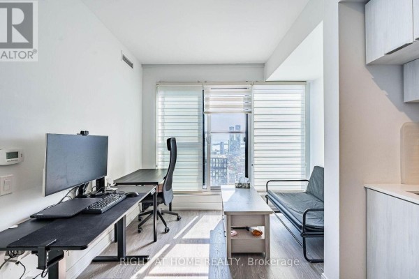 Apartment workspace with dual desks, computer, and window with city view. - 4608 - 181 Dundas Street E, Toronto