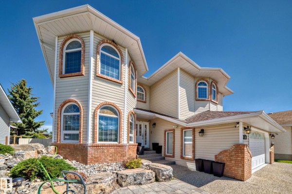 Close-up exterior view of the front entrance of a beige house with arched windows and brick detailing. - 4608 43 Av Nw, Edmonton