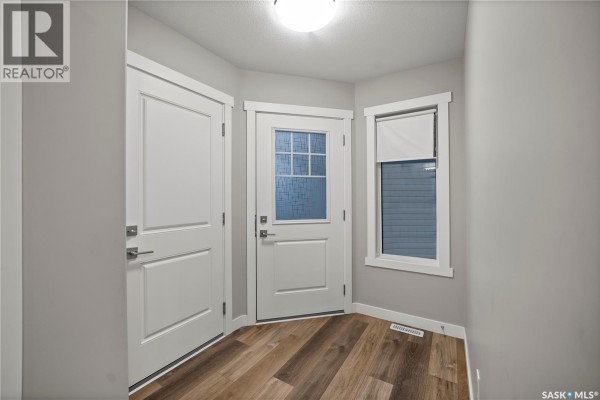 Entryway with two white doors, one with a glass pane, and wood-look flooring. - 4608 Mutrie Crescent, Regina