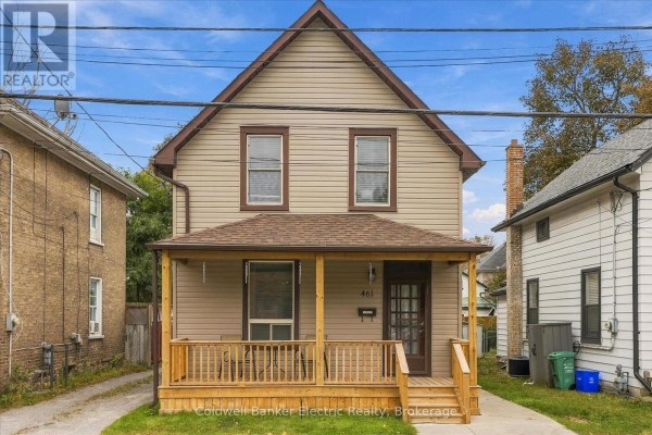 Front exterior view of a beige house with a wooden porch and steps during the day. - 461 Murray Street, Peterborough