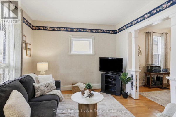 Living room with a sofa, television, and an archway leading to another room. - 461 Murray Street, Peterborough