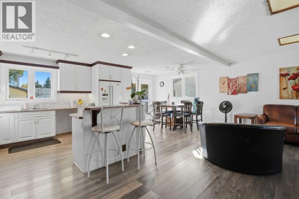 Open concept kitchen and dining area with white cabinets and wood floors. - 4615 31 Avenue Ne, Calgary