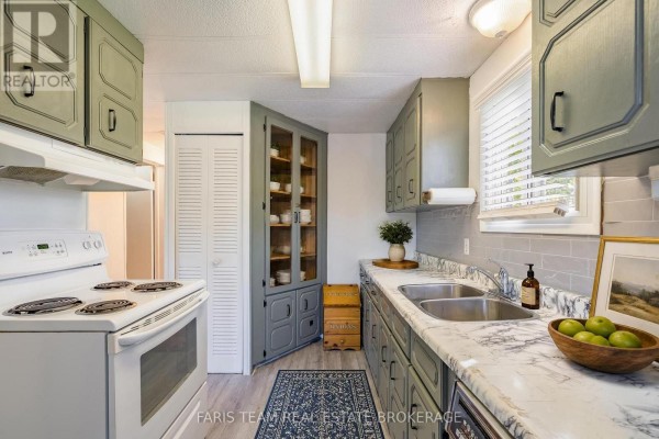 Kitchen with gray cabinets, white appliances, double sink, and a built-in hutch. - 4617 Concession Road 2 Sunnidale, Clearview