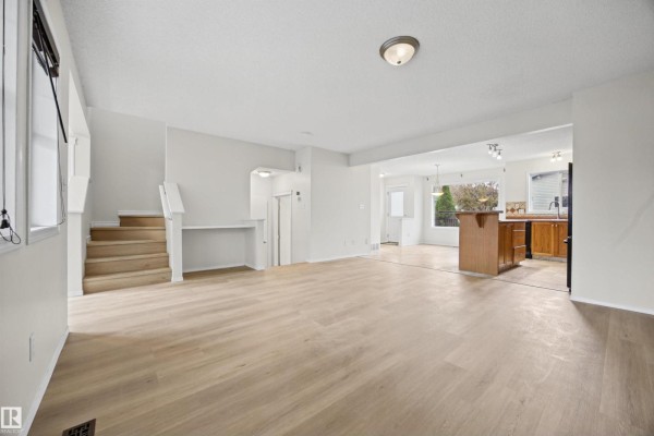 Living room with plush furniture, wood floors, guitars on wall, and open view to dining and kitchen. - 4618 Turner Square Sq Nw, Edmonton