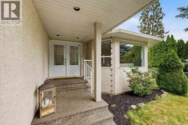 Close-up of the covered front porch with double glass doors, stairs, and a decorative lantern. - 4619 Gordon Drive, Kelowna