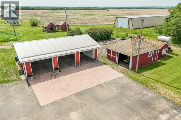 Aerial view of a large garage and red barn on a rural property with fields. - 46218 Rr 203, Rural Camrose County
