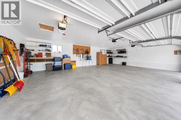 Interior of a spacious multi-bay garage with white walls, concrete floor, and storage shelves. - 46218 Rr 203, Rural Camrose County