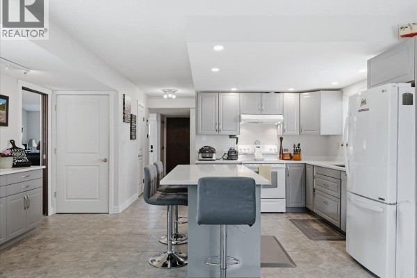 Bright kitchen with light grey cabinets, white quartz countertops, and a large island with grey stools. - 4628 Hermitage Drive, Richmond