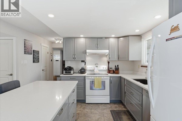 Kitchen view showing grey cabinets, white countertops, stainless steel appliances, and a window above the sink. - 4628 Hermitage Drive, Richmond