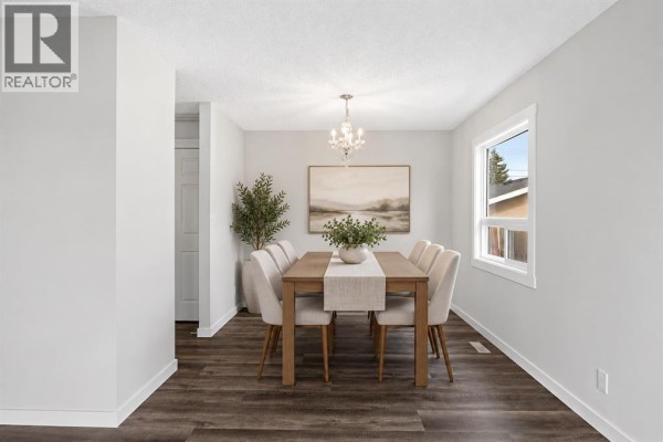 Dining room with a wood table, six chairs, and a chandelier. - 4628 Marcombe Road Ne, Calgary