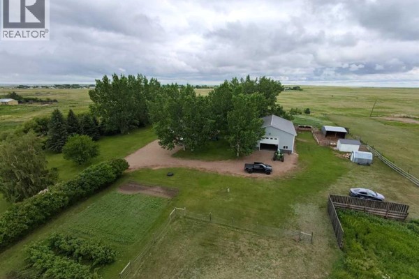 Aerial view of a spacious rural property with multiple buildings including a house, large garage, and several parked vehicles. - 463, 181043 Hwy 550, Rural Newell, County Of
