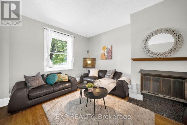 Living room with two dark leather sofas, a white rug, a fireplace, and a window. - 463 Slater Street, Ottawa