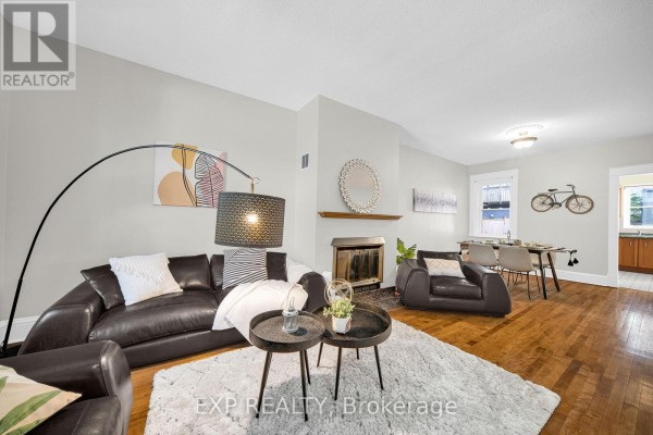 Living and dining area with a fireplace, dark leather furniture, dining table, and kitchen view. - 463 Slater Street, Ottawa